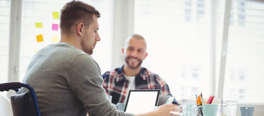 Två män, varav en är rullstolsburen, har ett samtal.