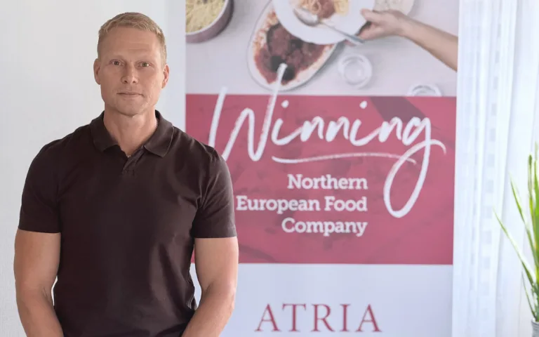 Ulrik Jismyr som är med i ledningsgruppen för Processtekniker inom hållbar livsmedelsproduktion står vid en skylt där det står Winning Northern European Food Company Atria. Han har blont kort hår och bär en brun pikétröja