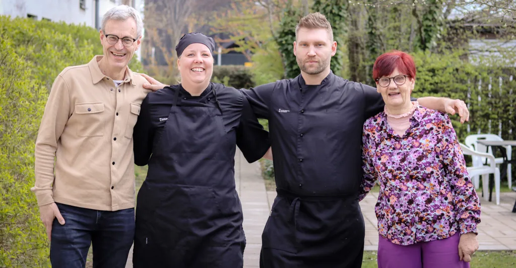 Från vänster till höger ser man i ordningsföljd Anders Lareke, Helena Woxblom, Niklas Lind och Christina Skjöldebrand som står i utomhusmiljö och håller armarna om varandra och ser glada ut. 