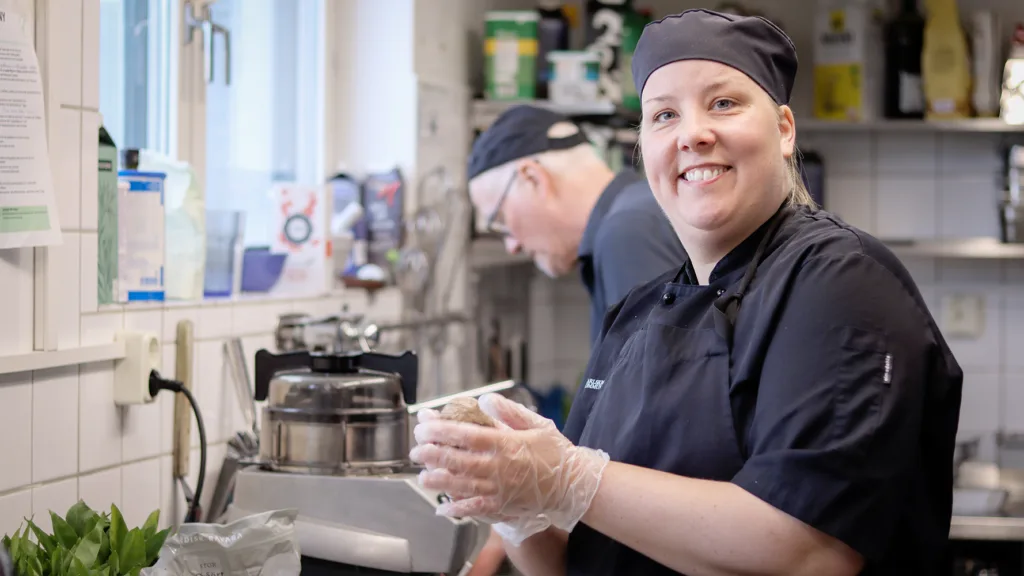 Helena, klädd i svarta kock-kläder, står i ett restaurangkök och rullar fiskpatéerna. I bakgrunden syns en manlig kock som arbetar. Helena tittar in i kameran och ser glad ut