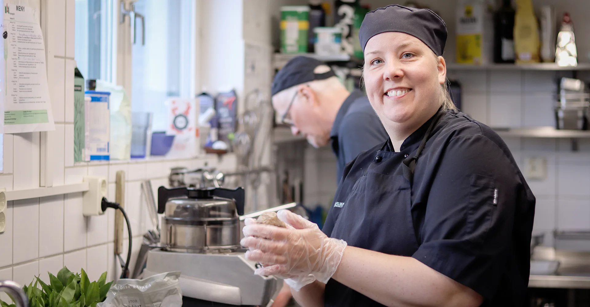 Helena, klädd i svarta kock-kläder, står i ett restaurangkök och rullar fiskpatéerna. I bakgrunden syns en manlig kock som arbetar. Helena tittar in i kameran och ser glad ut