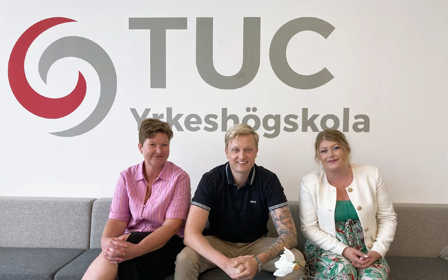 Hanna Kjellson, Alexander le Grand och Emelie Johansson på programmet Hotel & Restaurant Manager sitter i en soffa och tittar in i kameran. I bakgrunden syns TUC Yrkeshögskolas logotype.