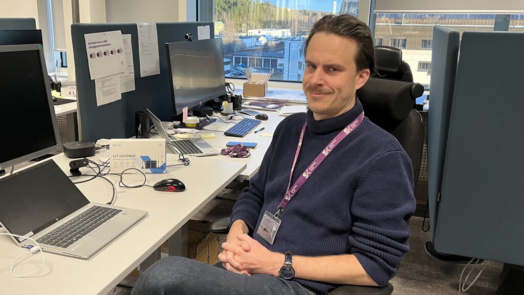 Gustav Hedenborg som läser programmet IoT-projektör sitter i ett kontorlandskap med en uppslagen laptop. Han tittar in i kameran.