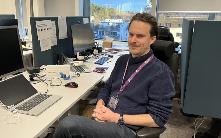 Gustav Hedenborg som läser programmet IoT-projektör sitter i ett kontorlandskap med en uppslagen laptop. Han tittar in i kameran.