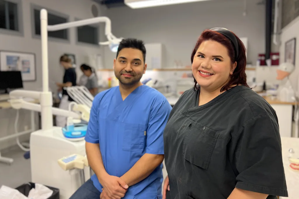 Mortaza och Gina ses i förgrunden iklädda bussaronger. I bakgrunden syns dentalrummet på TUC i Tranås